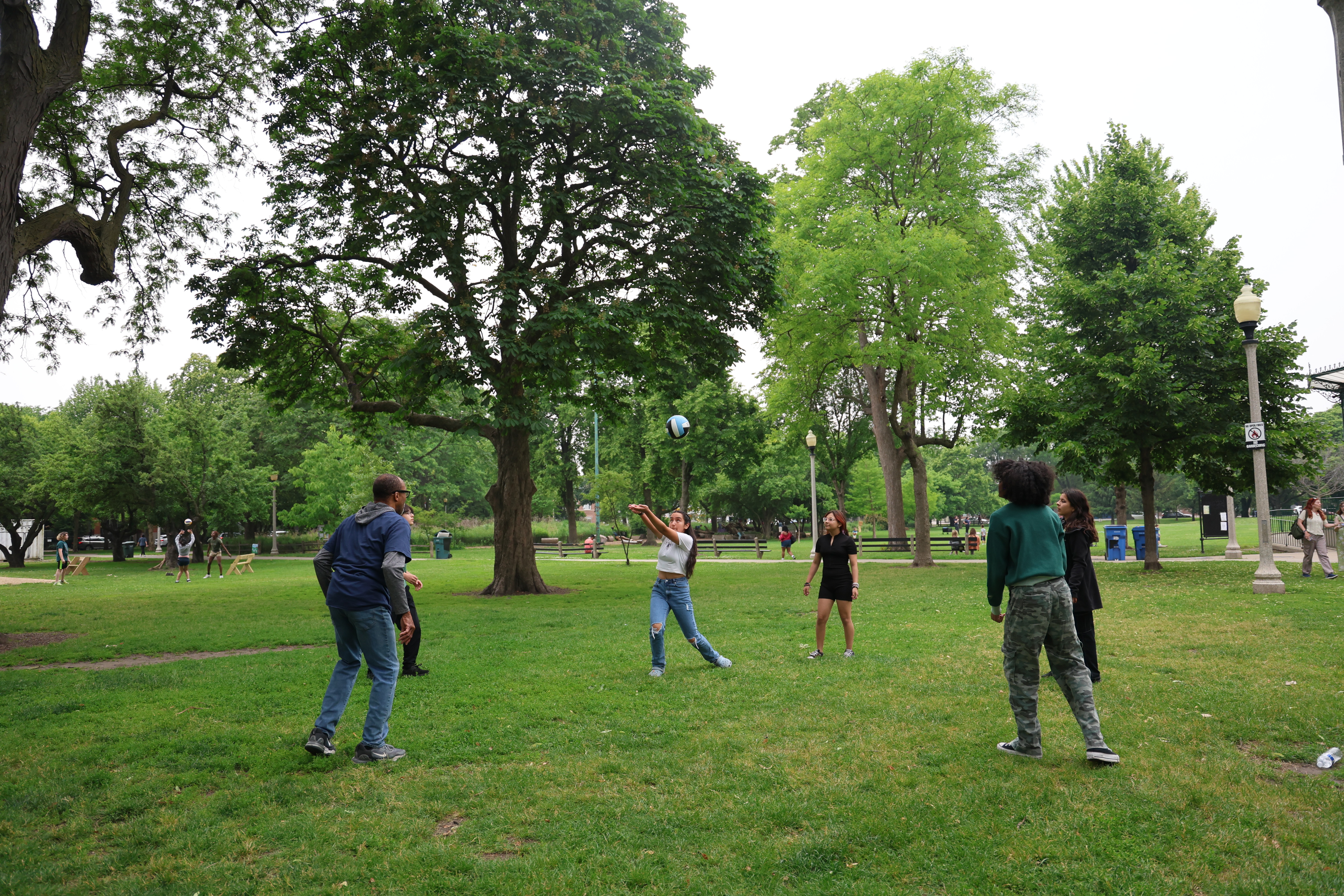 Friends play volleyball in a grassy park.
